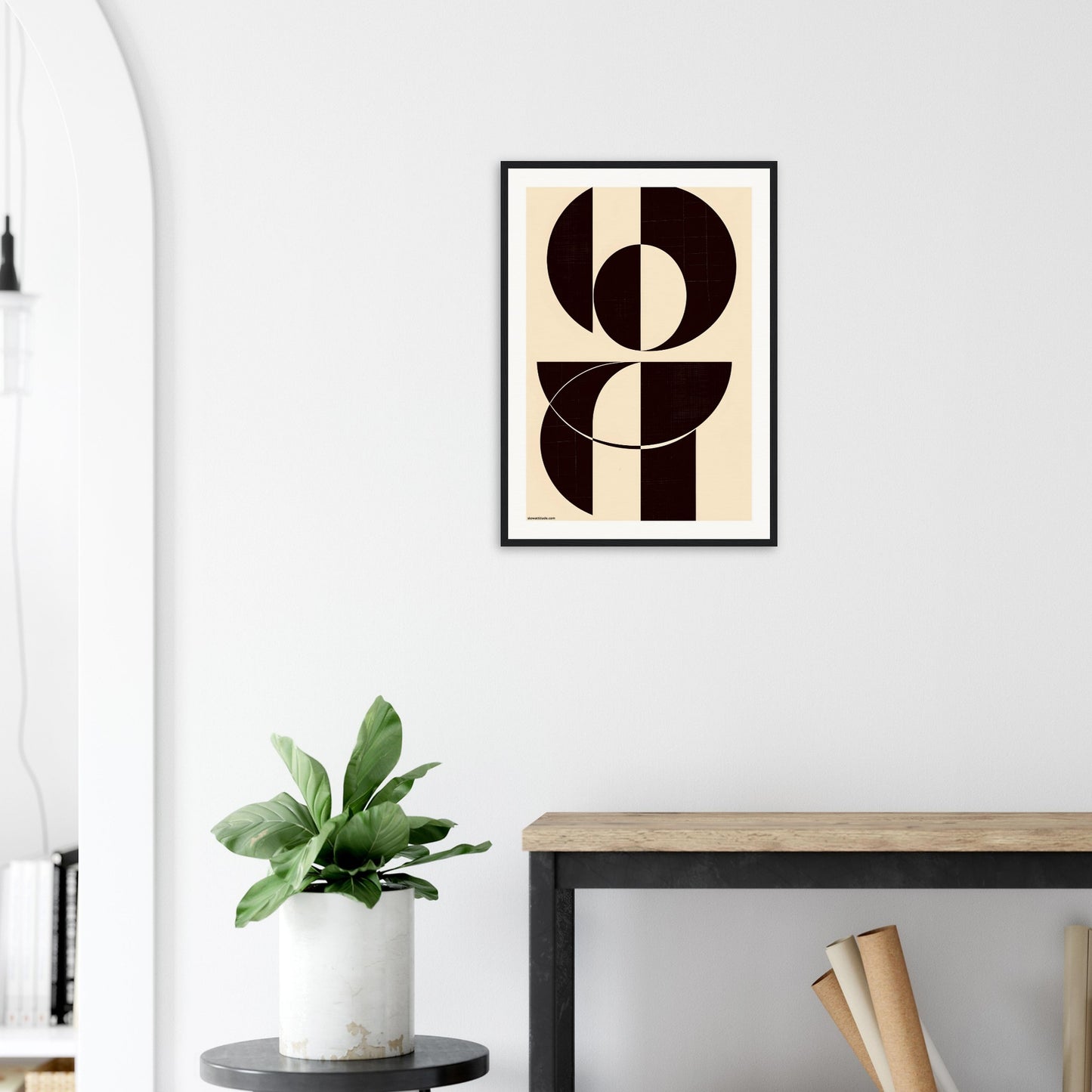 Abstract geometric framed art print inspired by the Bauhaus aesthetic placed on a wall above a desk with a plant and books.