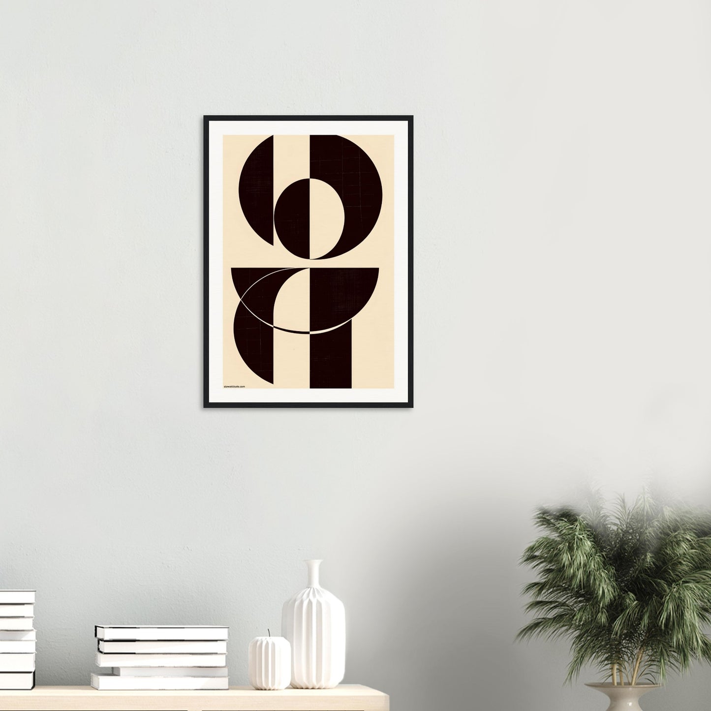Abstract art print in a black frame on a wall above a shelf with decorative items.