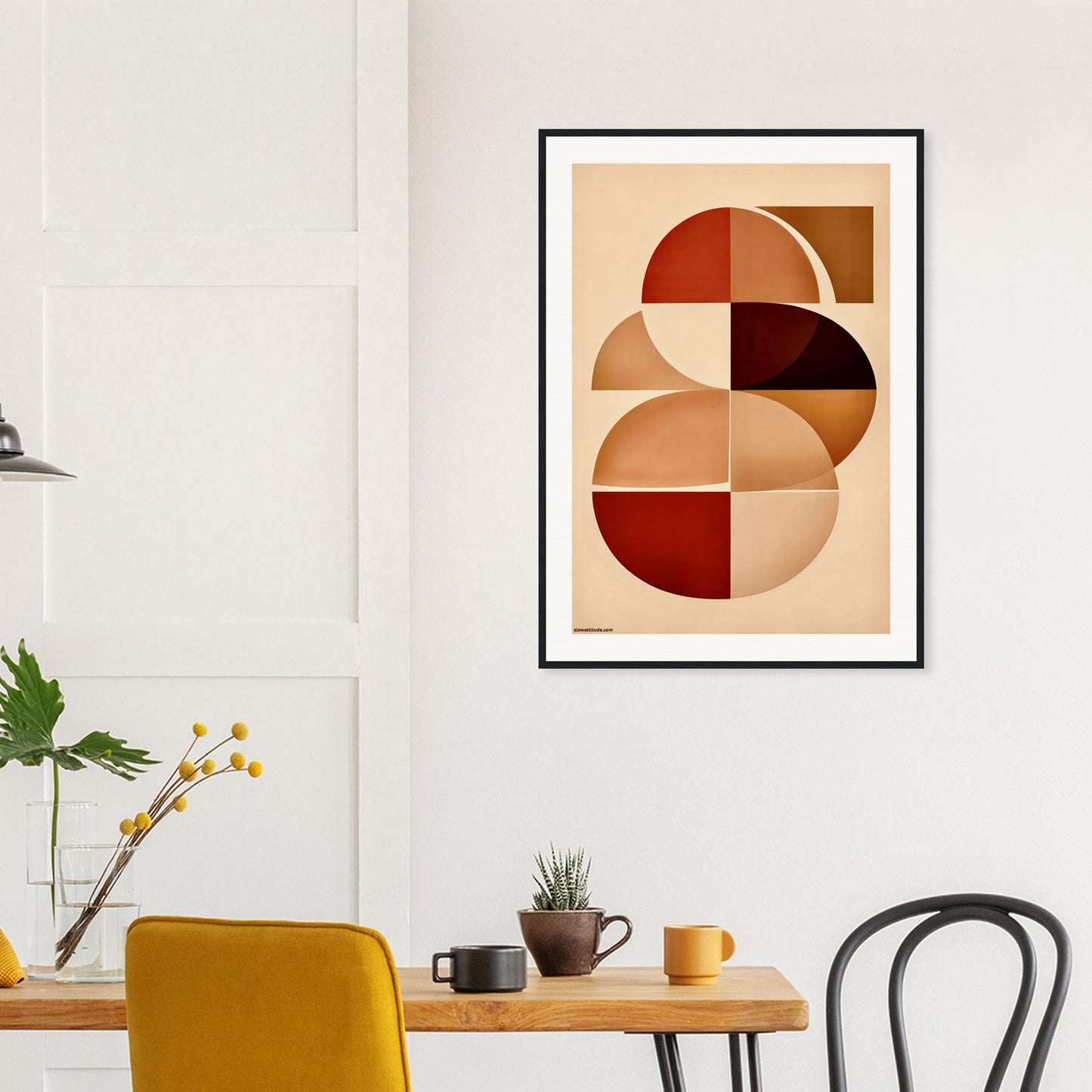 Abstract framed art print on a wall above a wooden table with chairs.