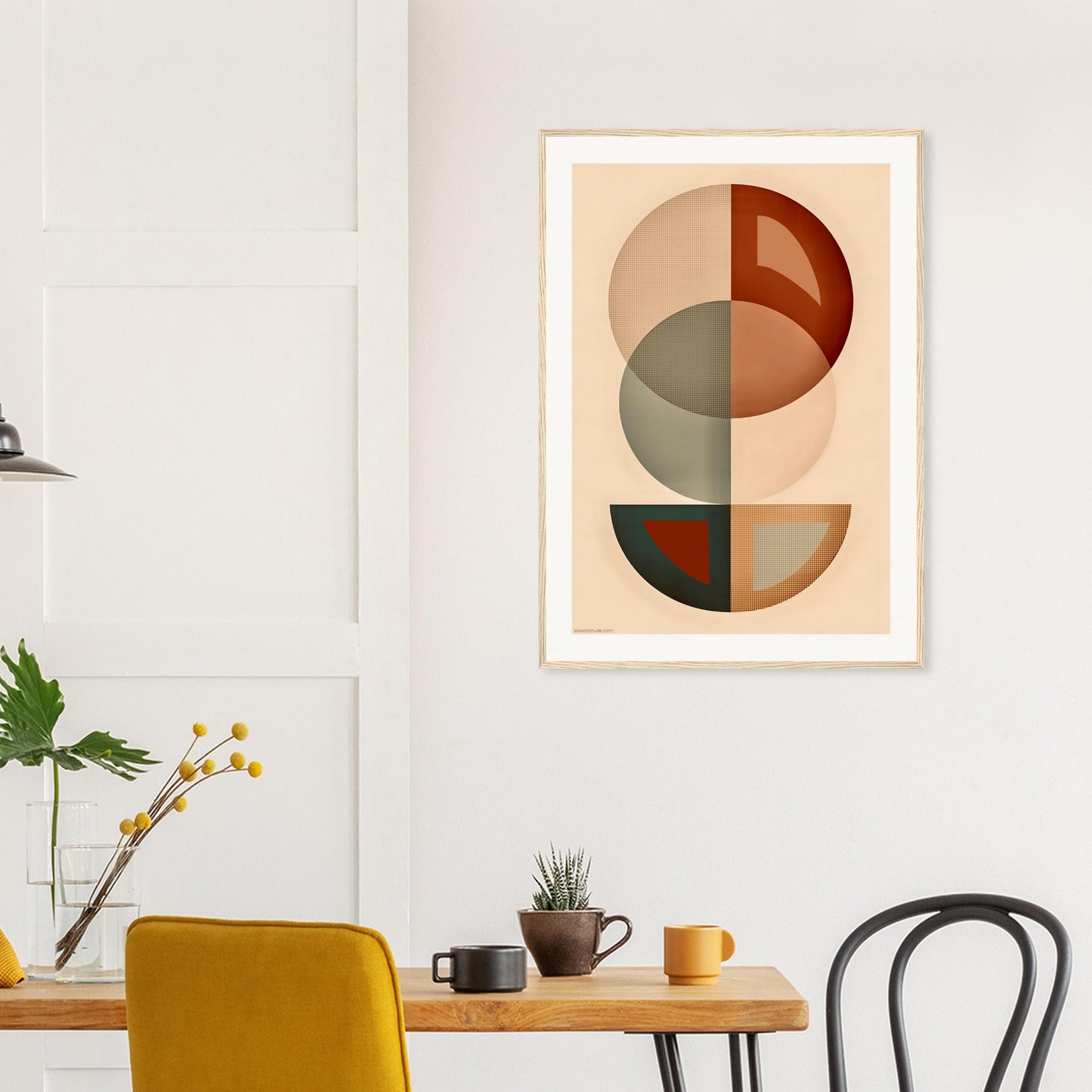 Abstract art print on a wall above a wooden table with chairs.