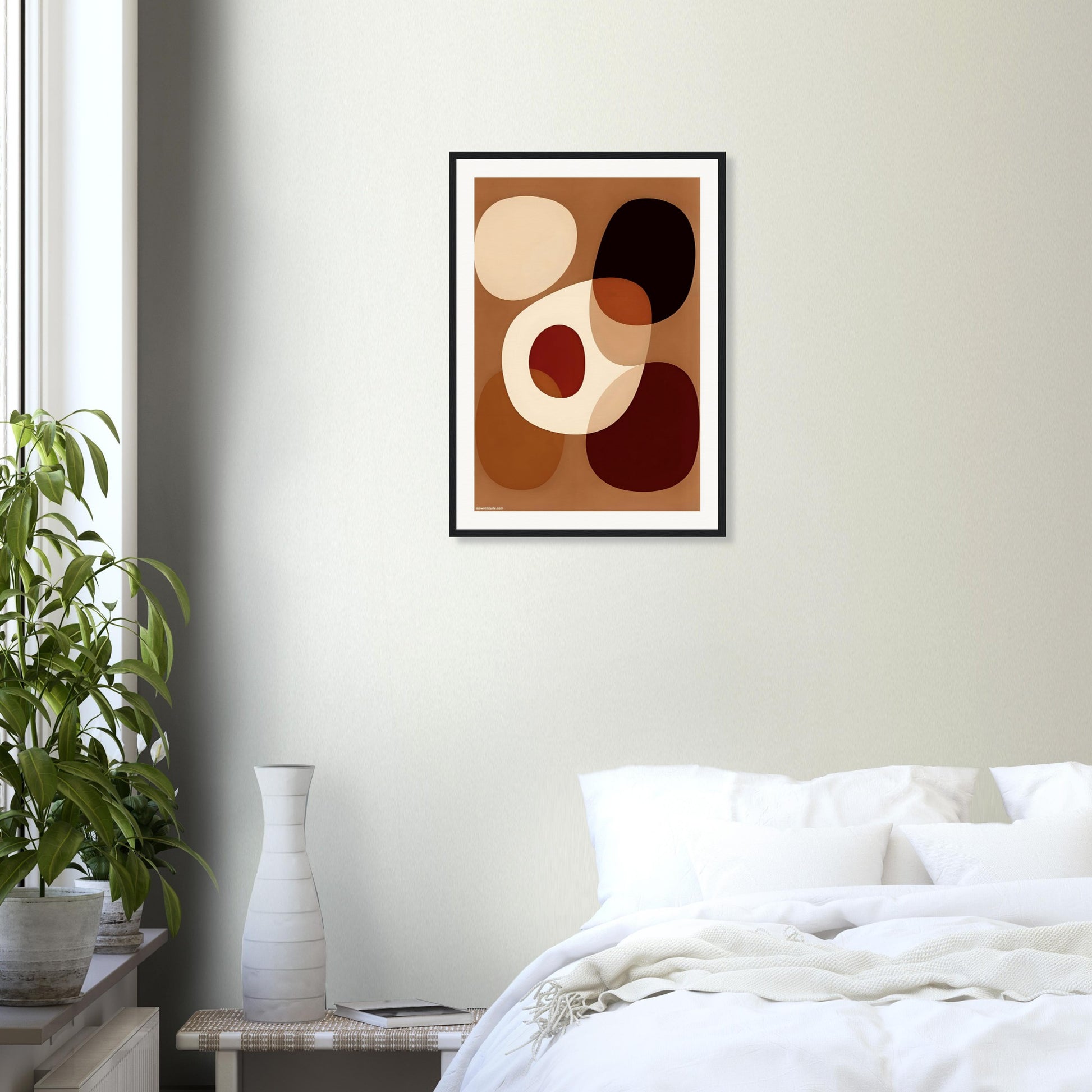 Framed abstract art piece on a wall above a bed in a bedroom setting.