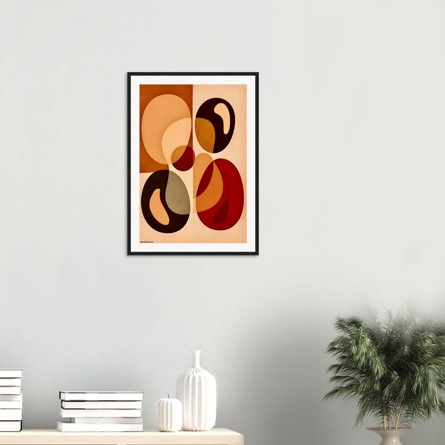 Framed abstract art piece with organic shapes on a wall with decorative items below.