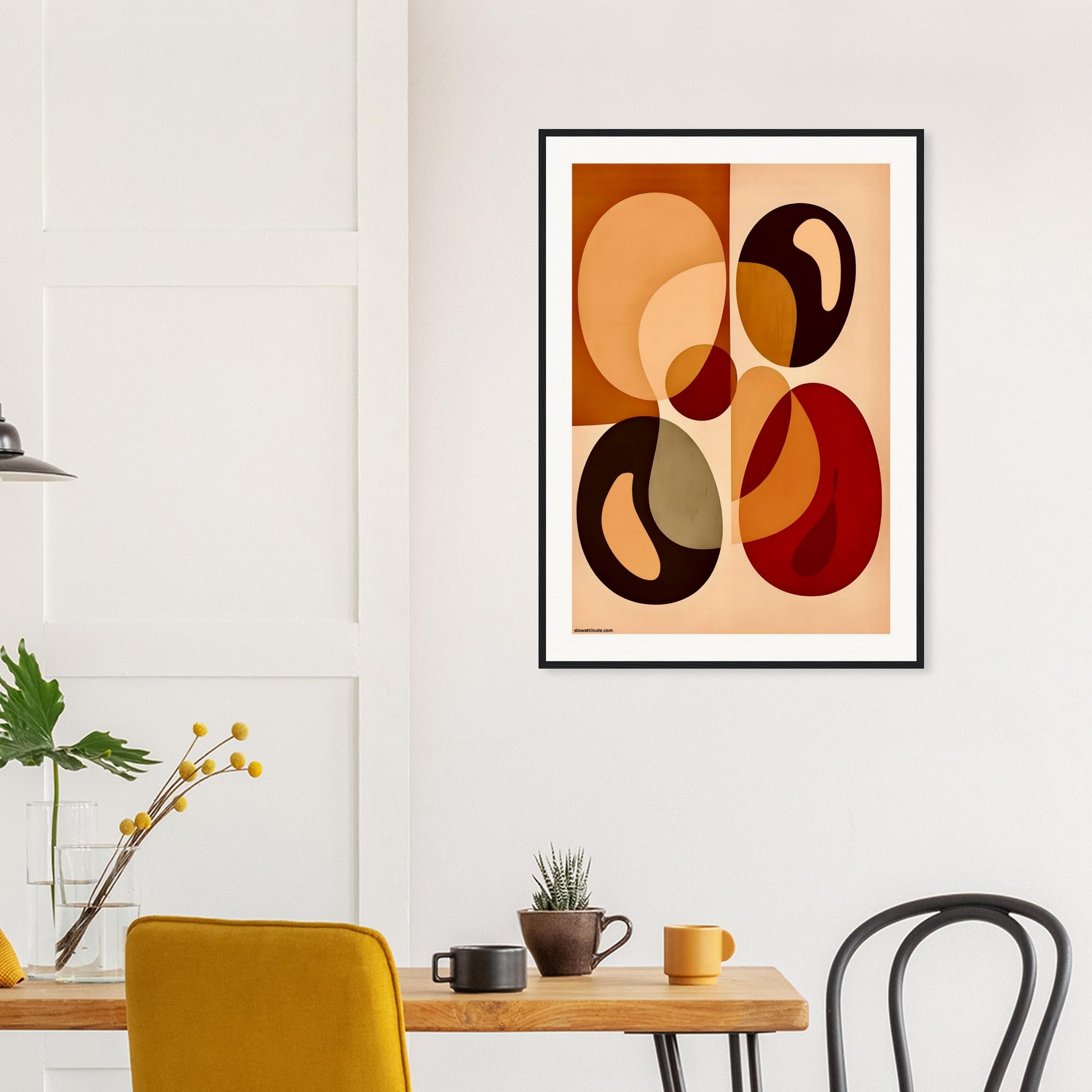 Abstract geometric art print in a black modern wooden frame on a wall above a dining table with chairs.