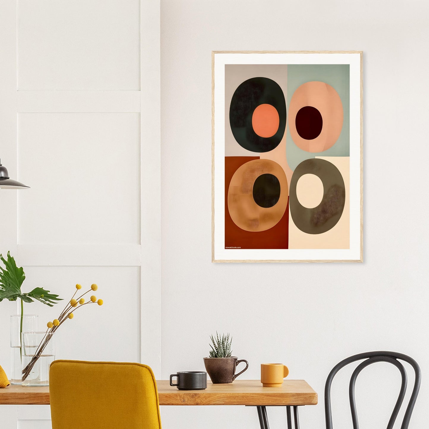 Abstract art print on a wall above a dining table with chairs.