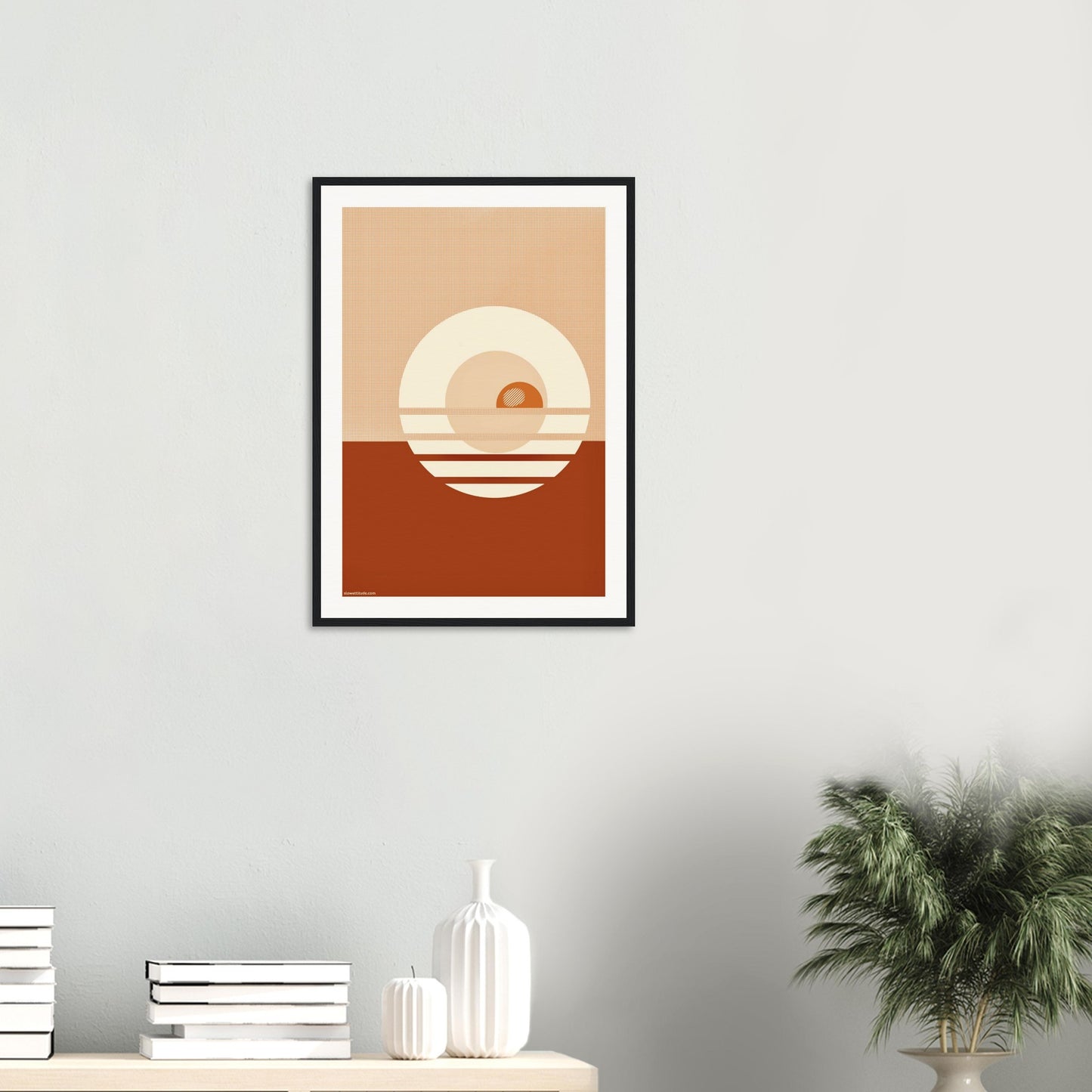 Framed abstract art print on a wall with decorative items below.