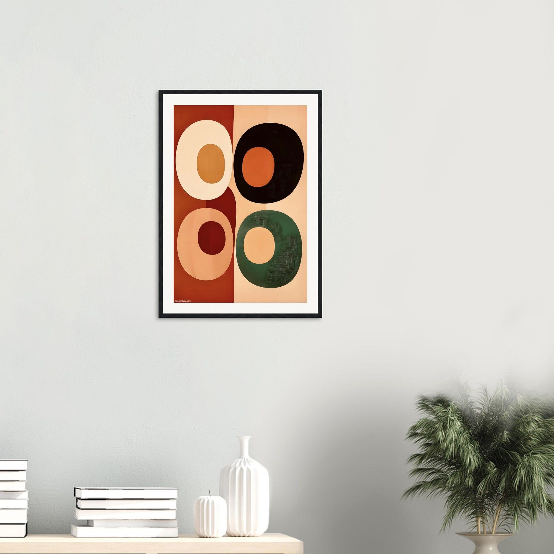 Framed abstract art print with geometric shapes on a wall above a shelf.