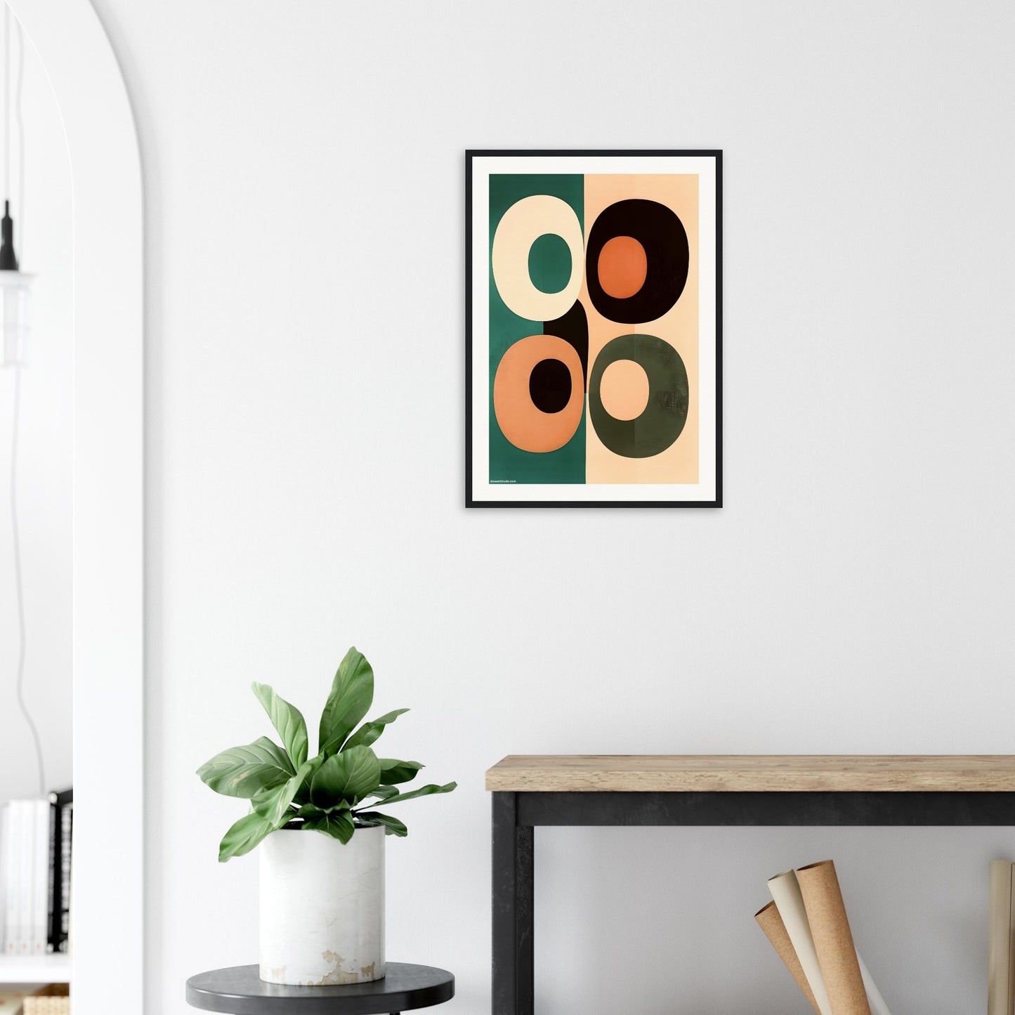 Abstract art print on a wall above a desk with a plant