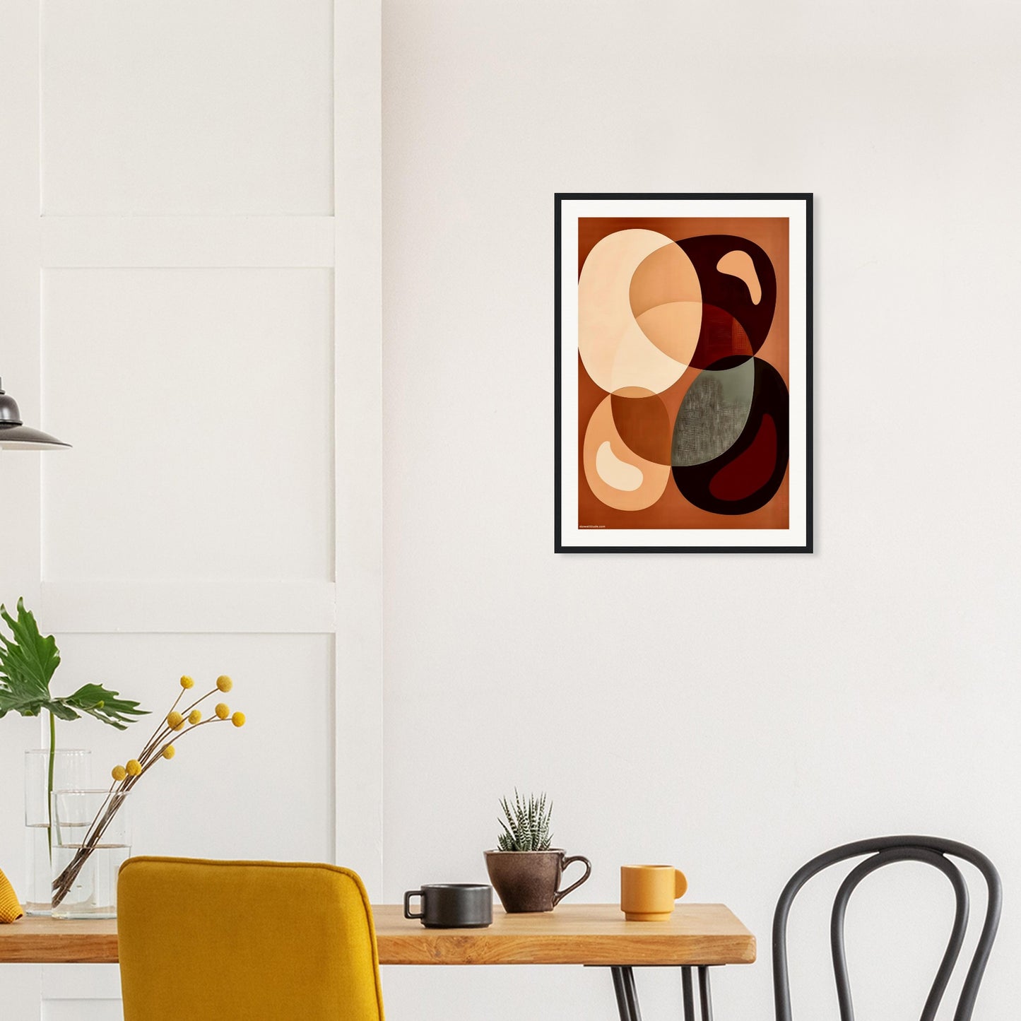 Abstract art print on a wall above a dining table with chairs.