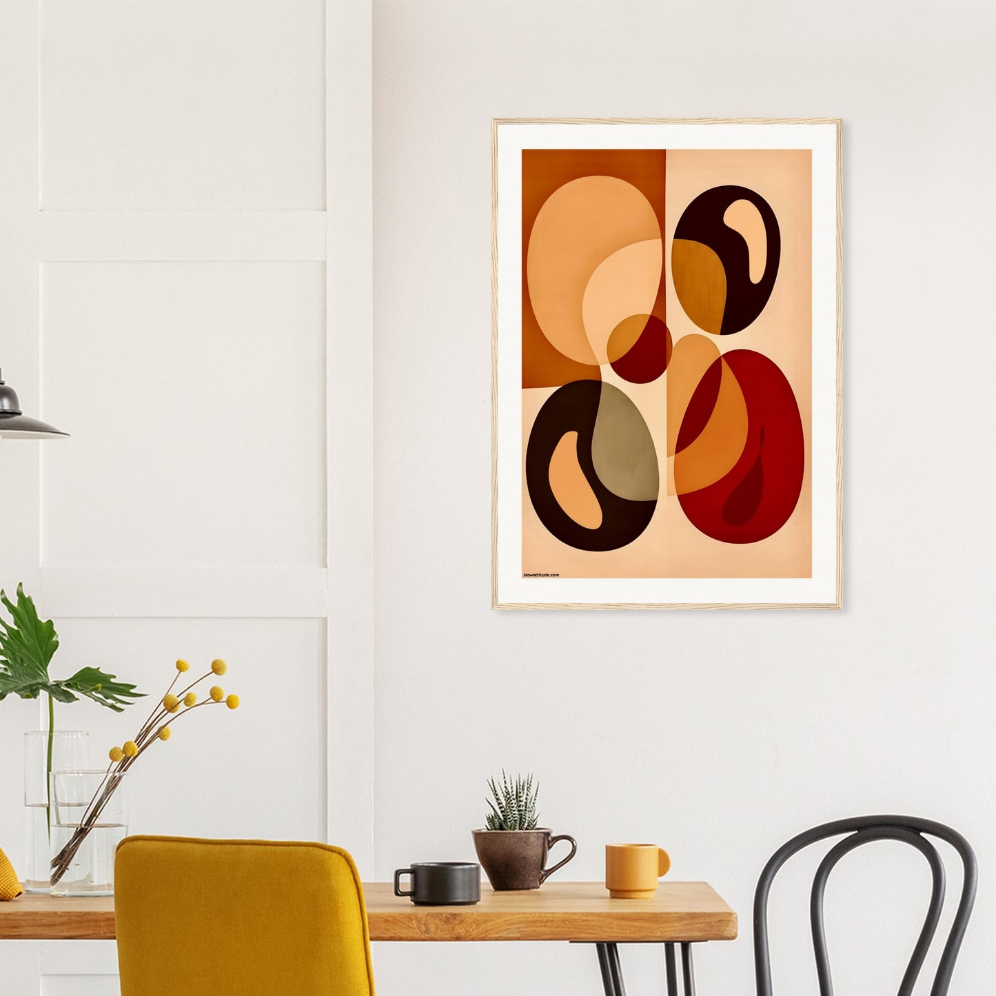 Abstract art print with round shapes on a wall above a wooden table with chairs.
