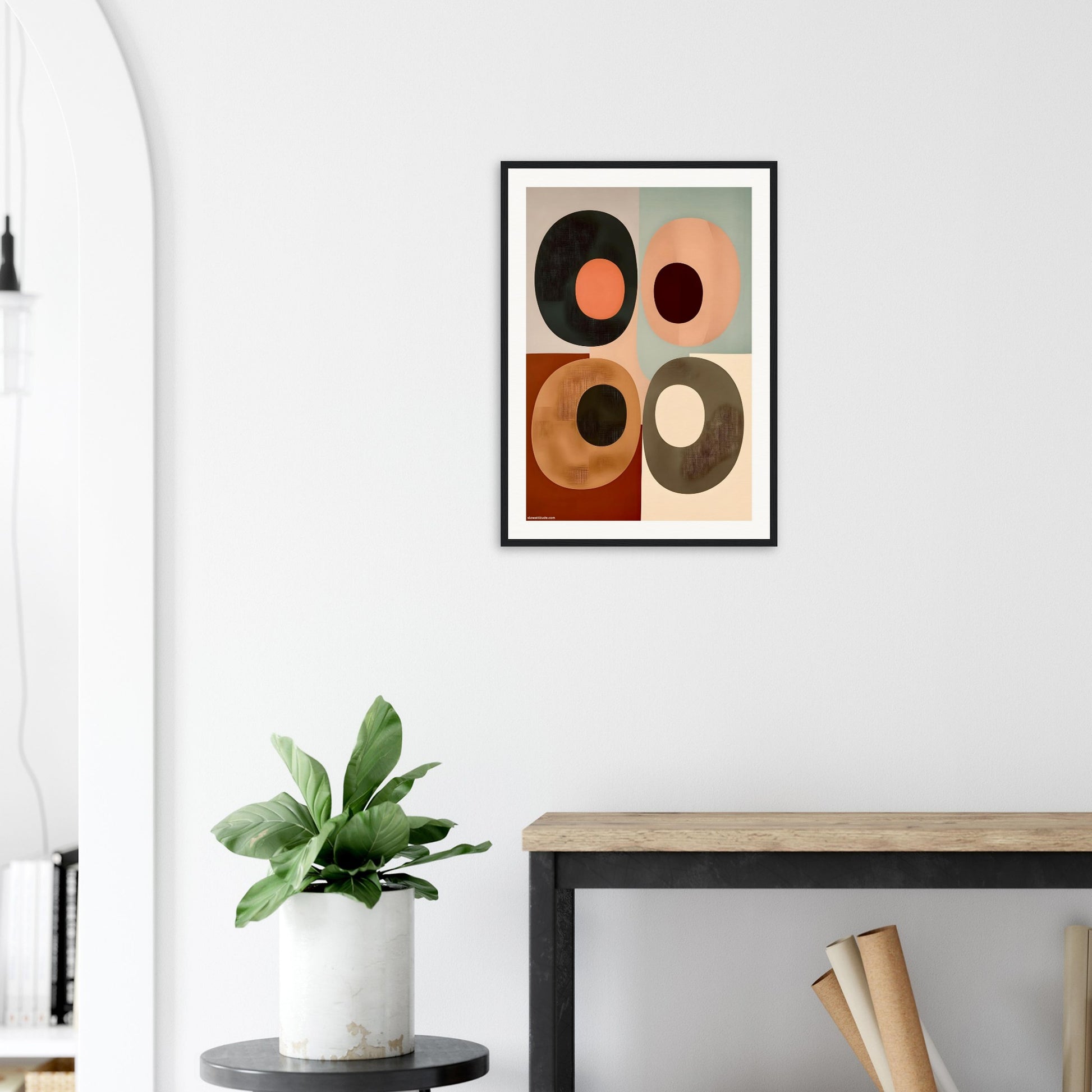 Abstract art print on a wall above a desk with a plant